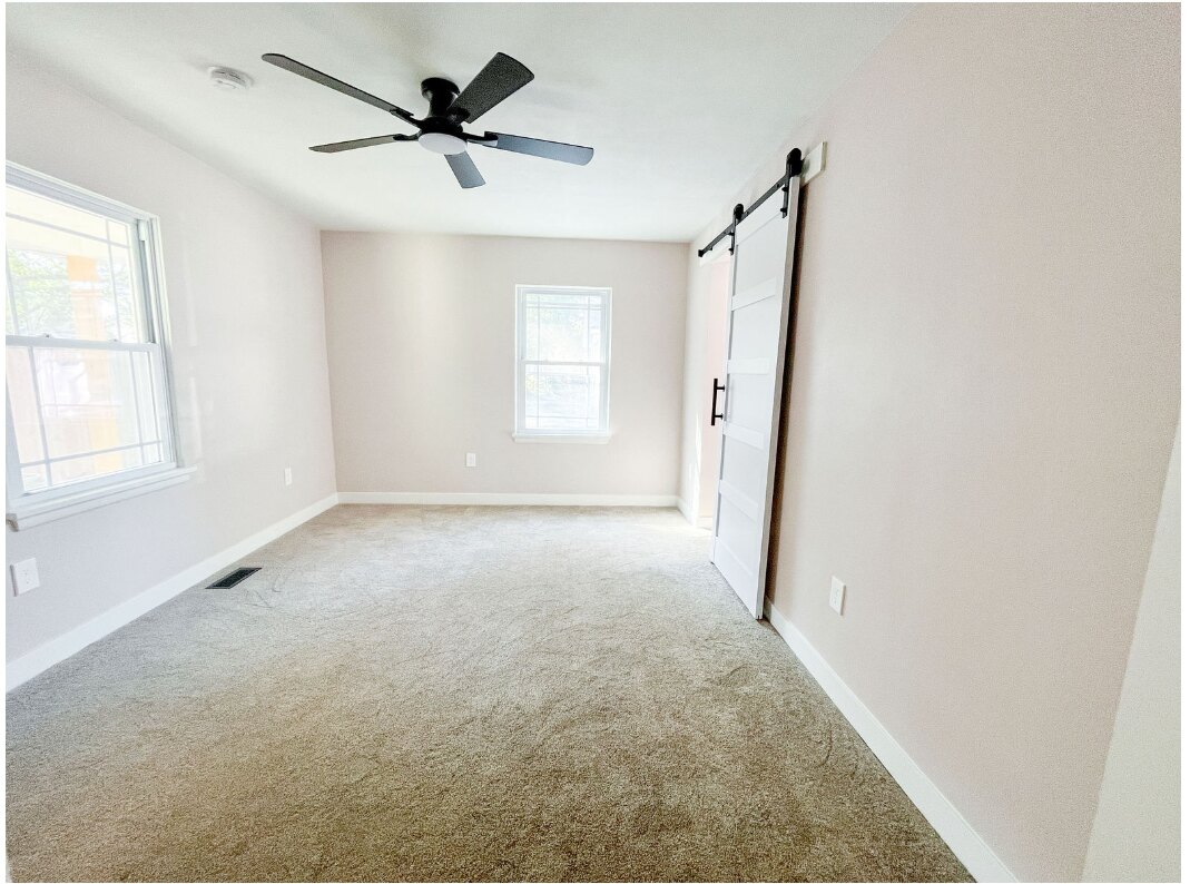 Completed primary bedroom with bathroom barn door